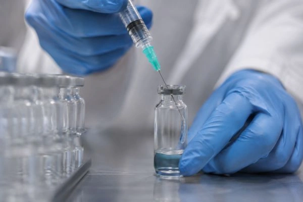 Researcher adding solvent into vial during reconstitution